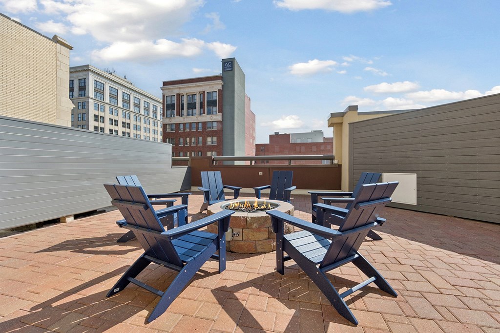 A patio with blue chairs and a fire pit.