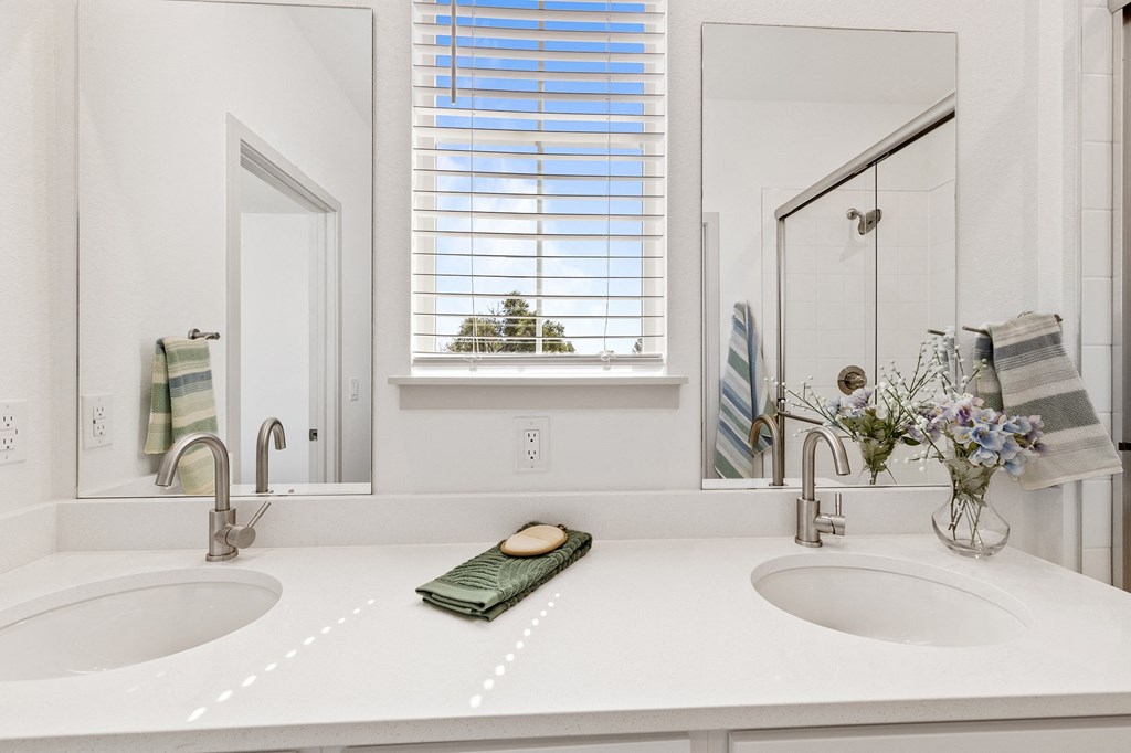 a white bathroom with two sinks and a mirror