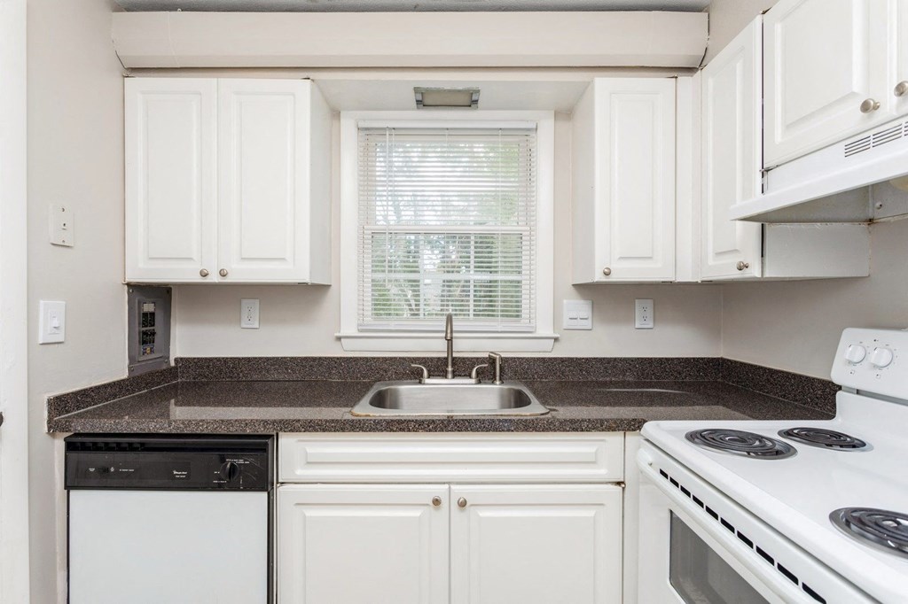 a kitchen with white appliances and granite counter tops and white cabinets