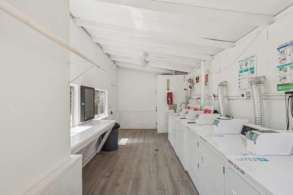 A clean, white-walled room with wood flooring and a row of white cabinets.