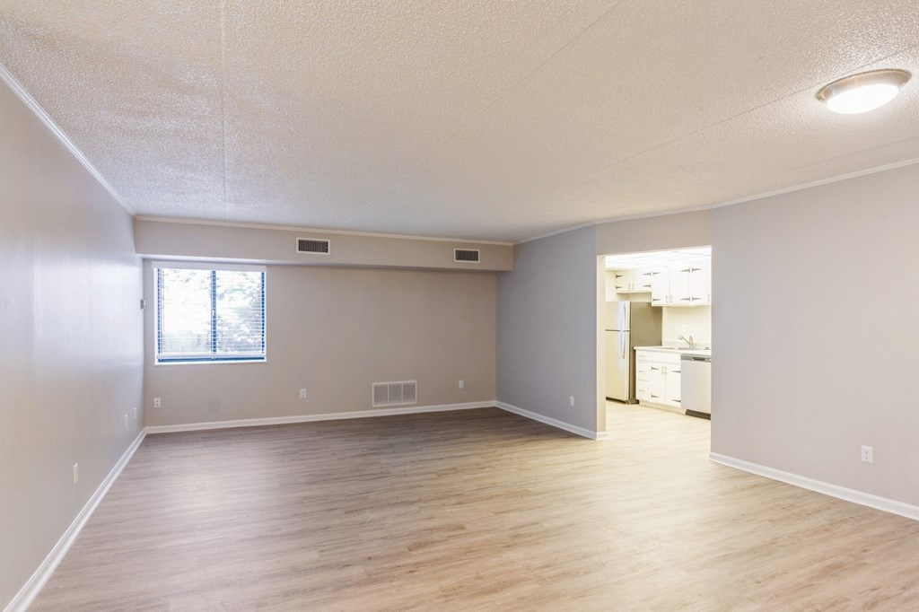 A spacious living room with wooden flooring and a window.