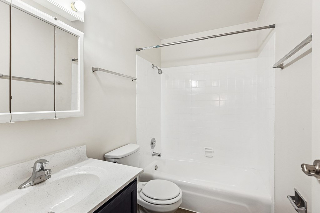 A white bathroom with a toilet, sink, and bathtub.