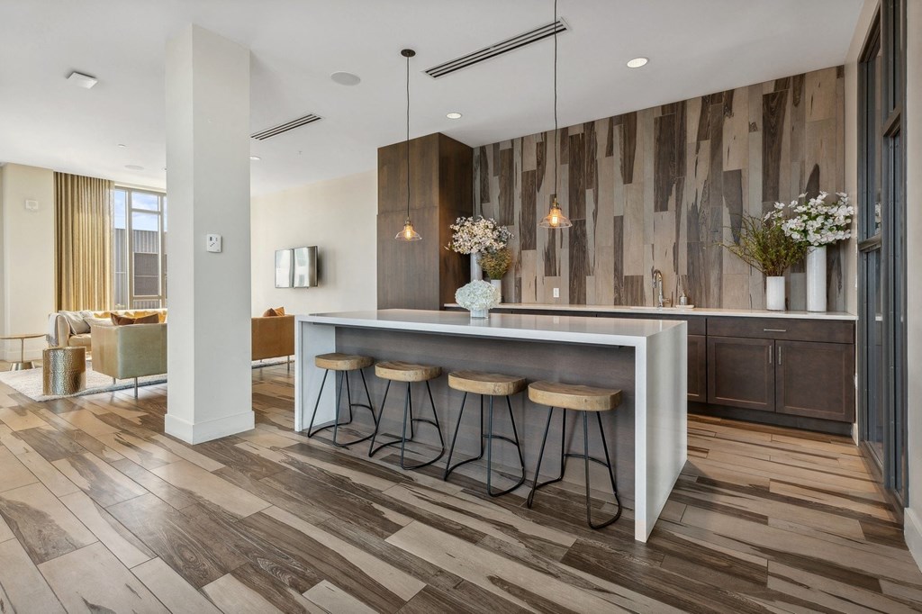 a kitchen with wooden floors and a bar with three stools at The Rowe, Grand Rapids