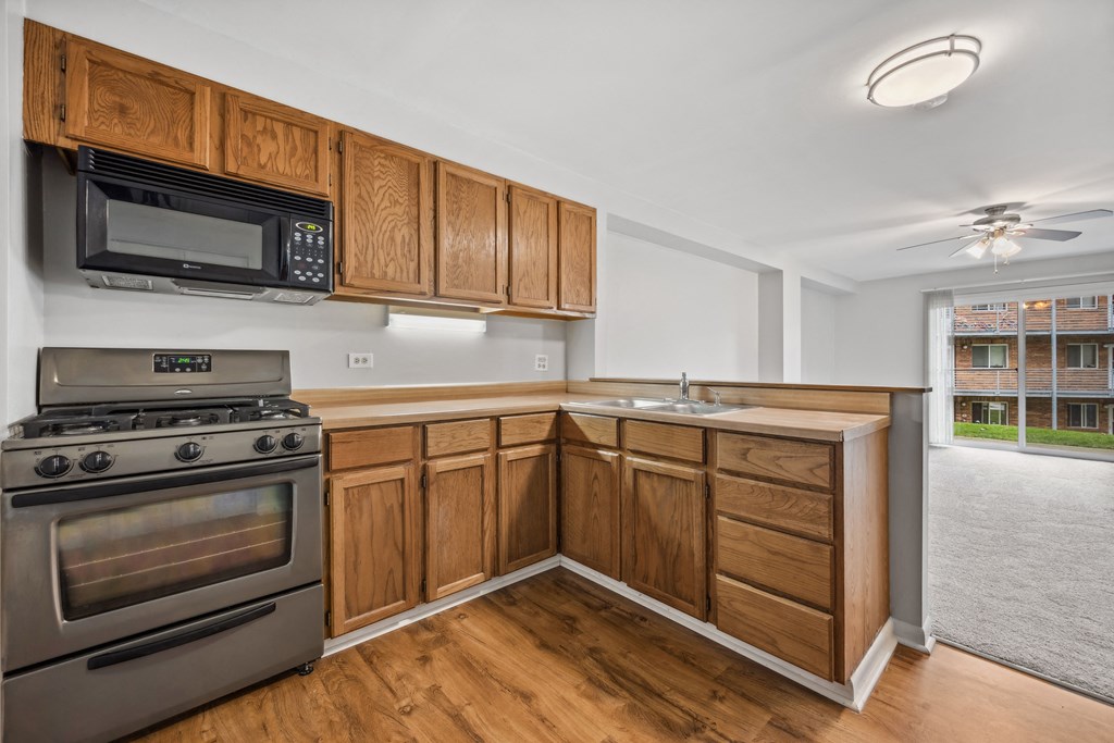 White interior with wooden cabinets and black appliances at River Oaks, North Aurora, 60542