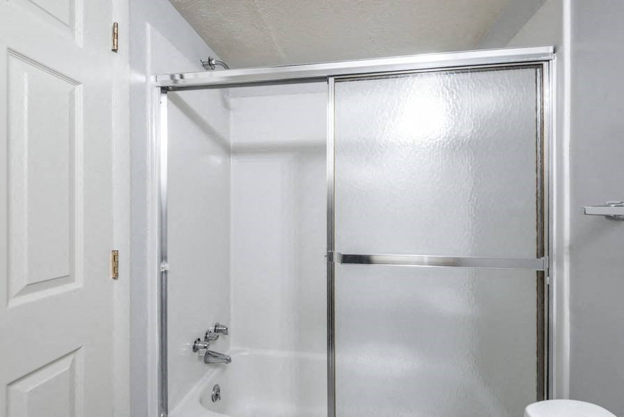 A white door with a silver handle and a white toilet in a bathroom.