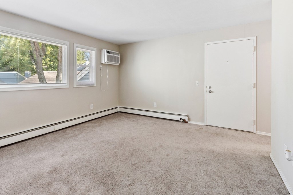 A room with a carpeted floor, a window, and a door.