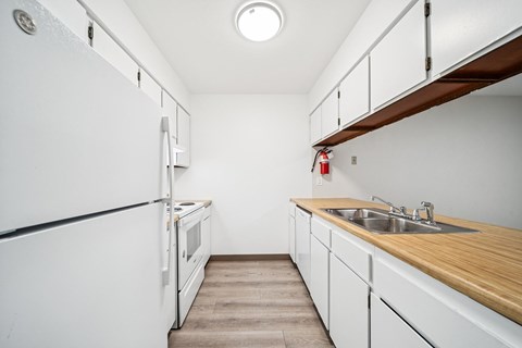A kitchen with white appliances and wooden countertops.