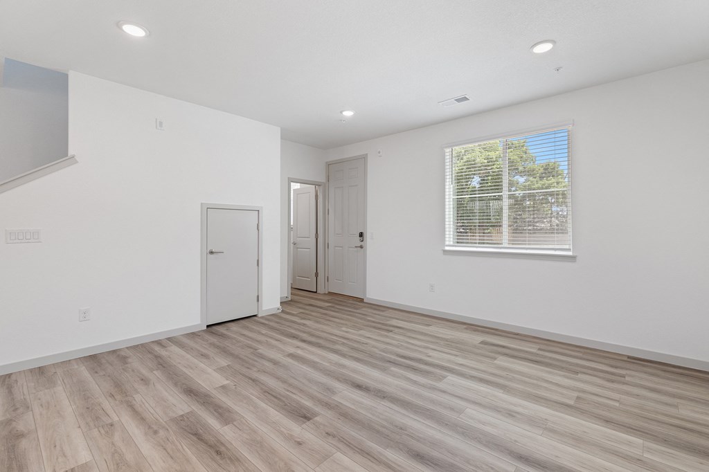 a living room with white walls and wood flooring and a window