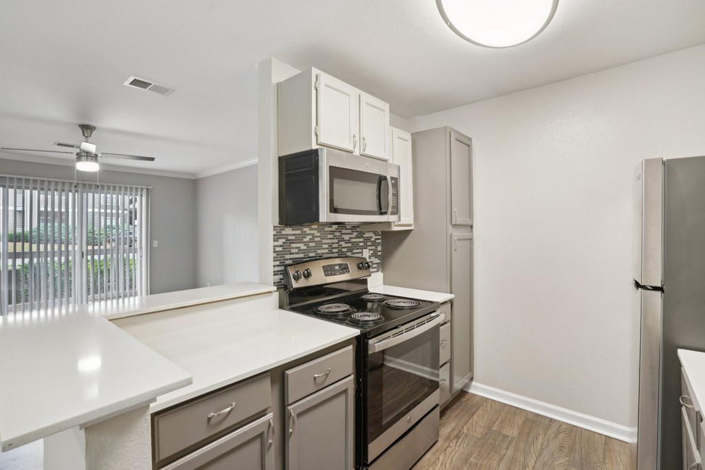 A kitchen with a white counter top and stainless steel appliances.