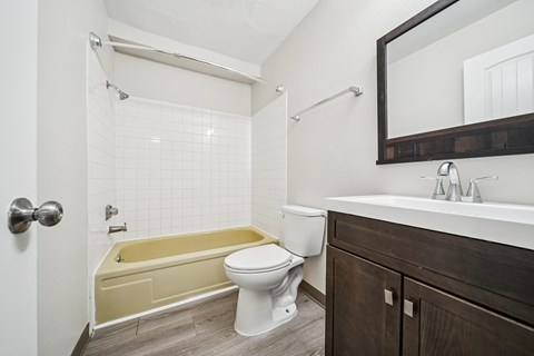 A white toilet sits next to a yellow bathtub in a bathroom.