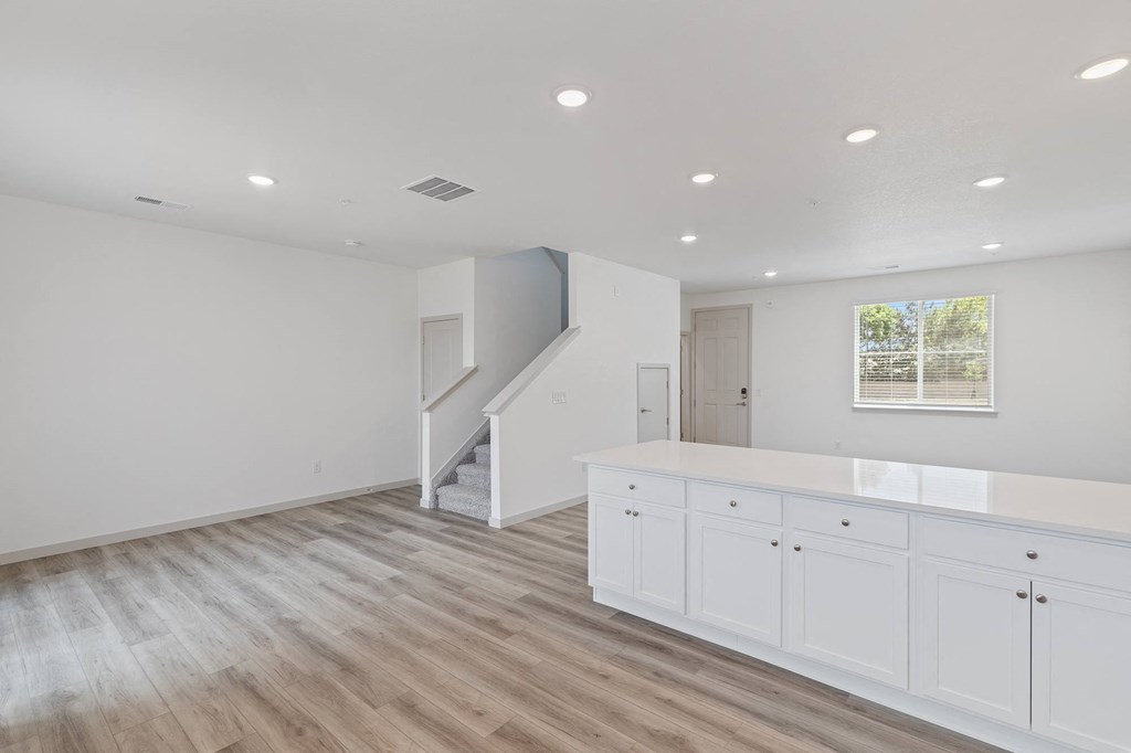 a white kitchen with white cabinets and a staircase