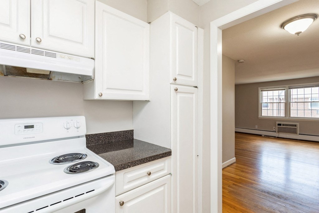 an empty kitchen with white appliances and white cabinets