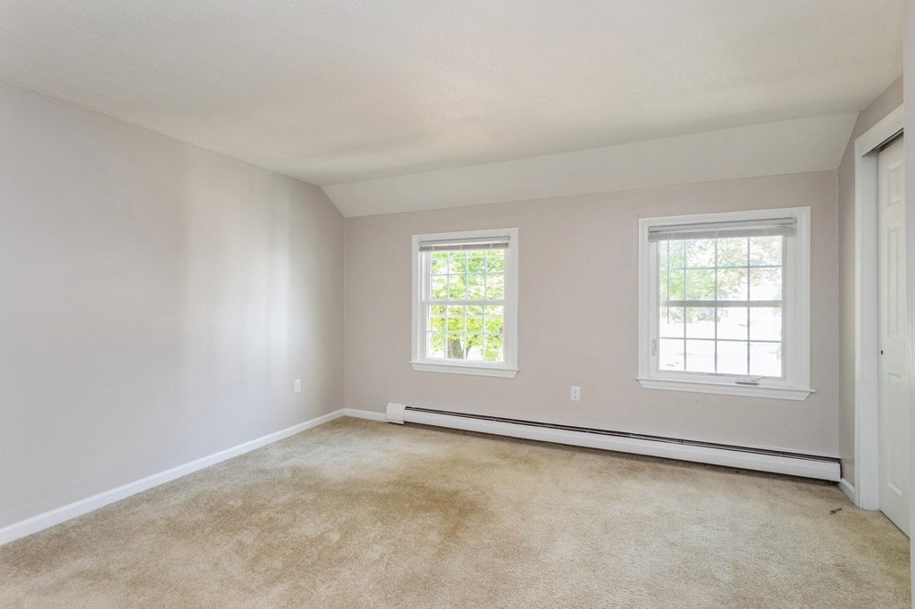 an empty bedroom with two windows and a carpeted floor