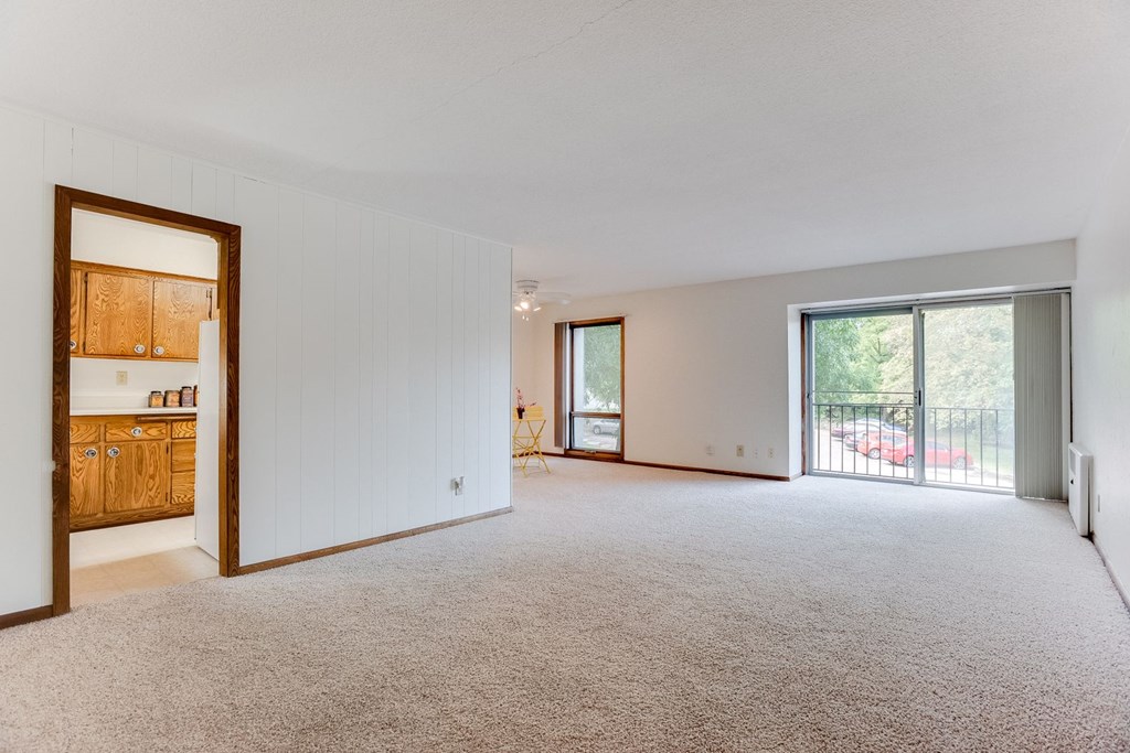 A large living room with carpeted floor and white walls.