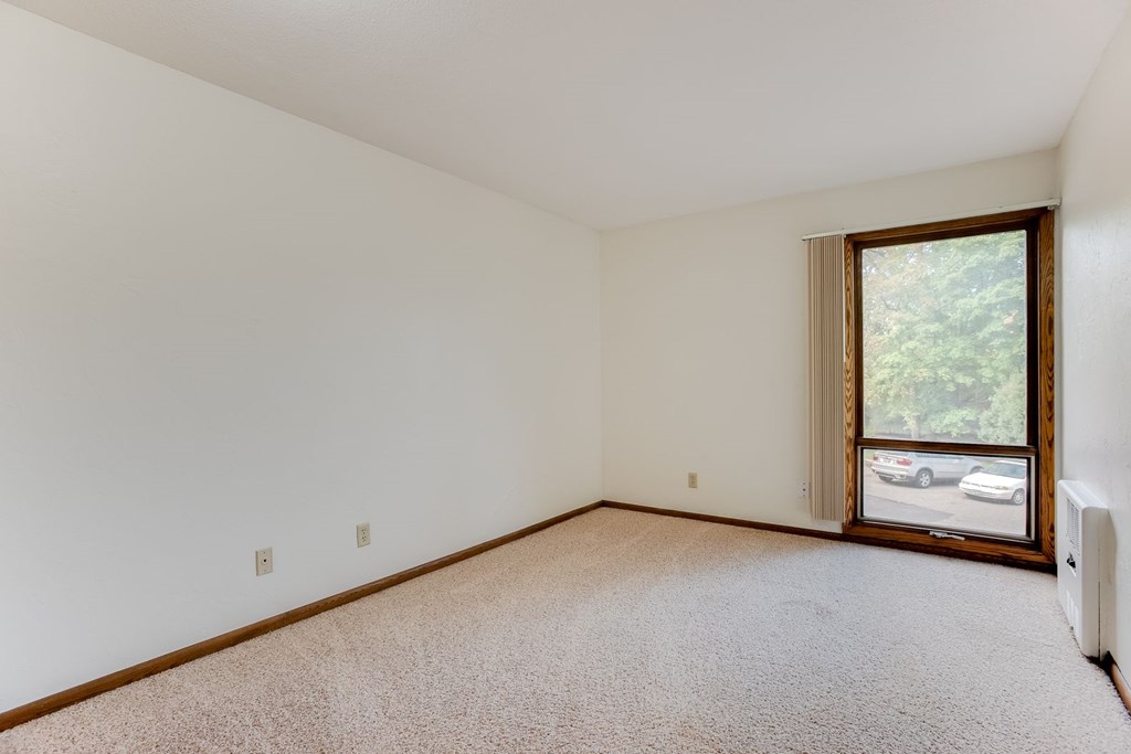 A bedroom with a window and white walls