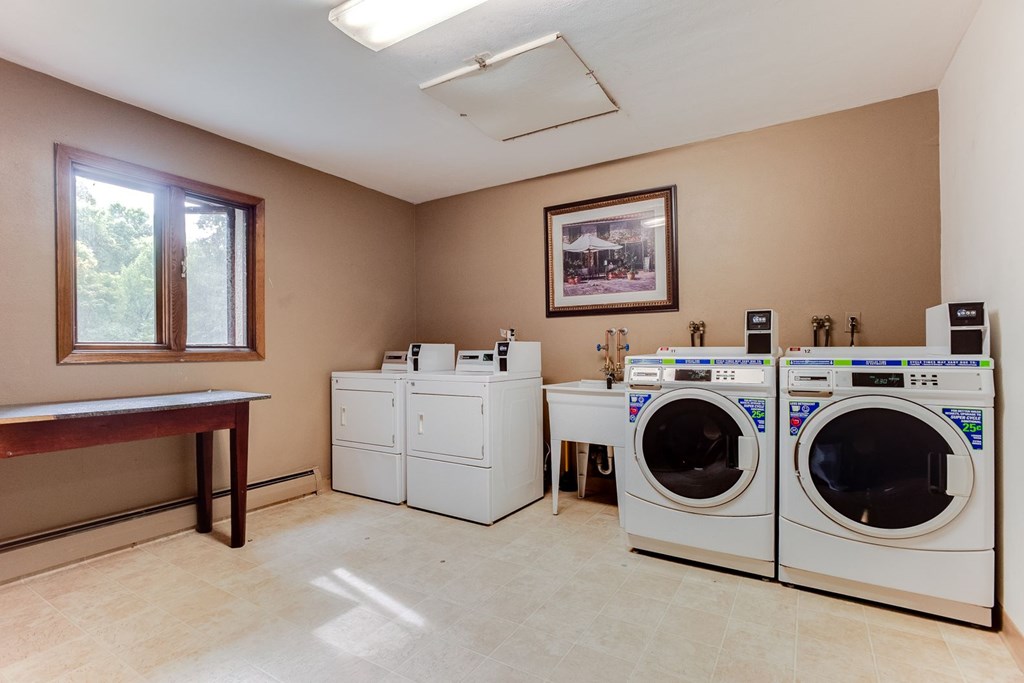 A laundry room with a washer and dryer on the right and a table on the left at Wayzata Woods Apartments, Wayzata, MN