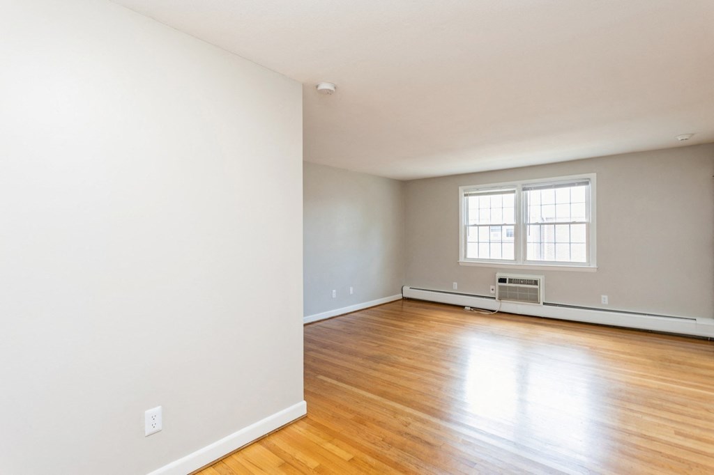 the living room of an empty house with white walls and wooden floors
