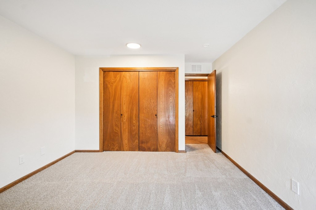 A room with a carpeted floor and two wooden doors.