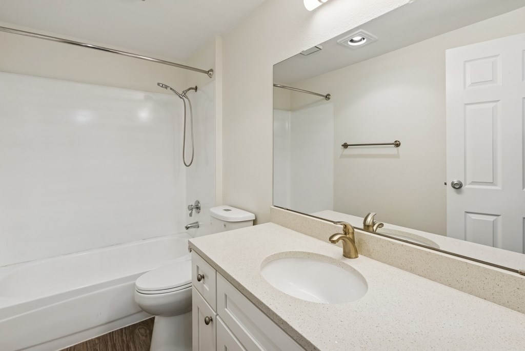 A white bathroom with a toilet, sink, and bathtub.