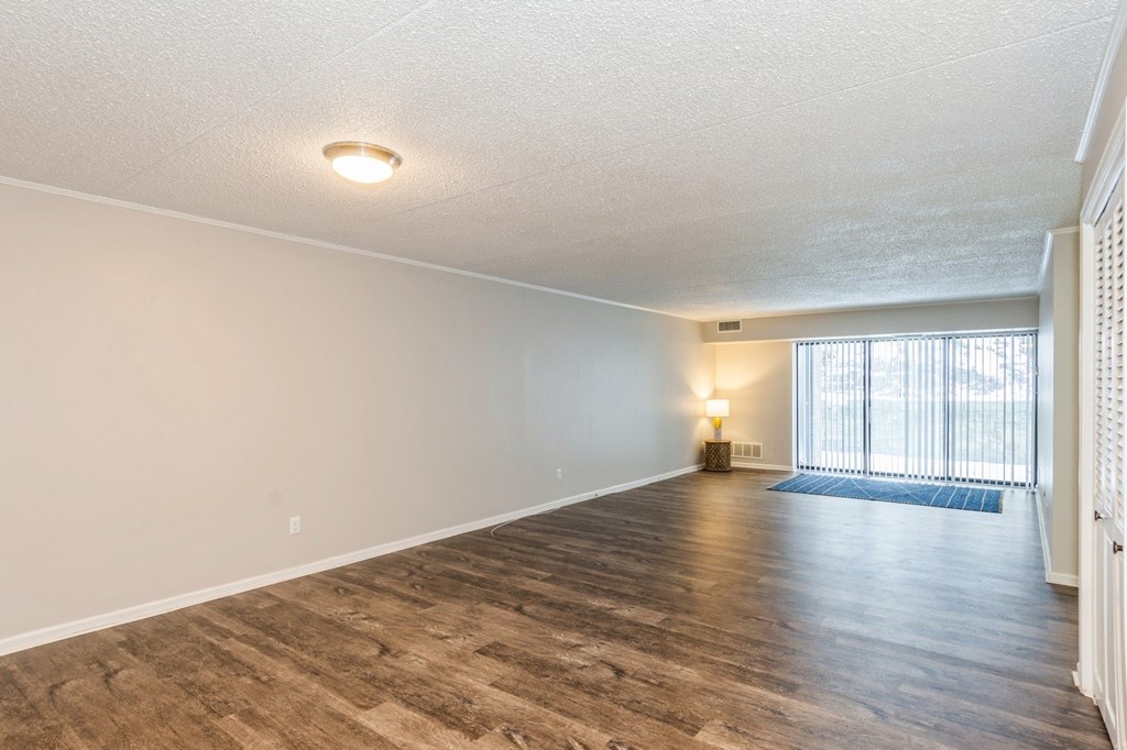 A spacious living room with wooden flooring and a window