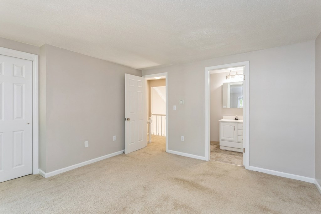 empty room with two doors with one on looking at the hallway and one into the bathroom