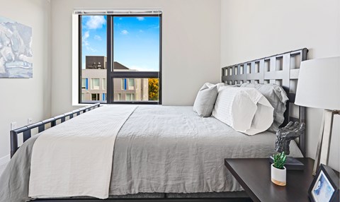 Bedroom with modern bed and city views at Pure Lowry Apartments, Minneapolis, MN
