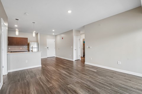 A spacious room with wooden flooring and white walls.