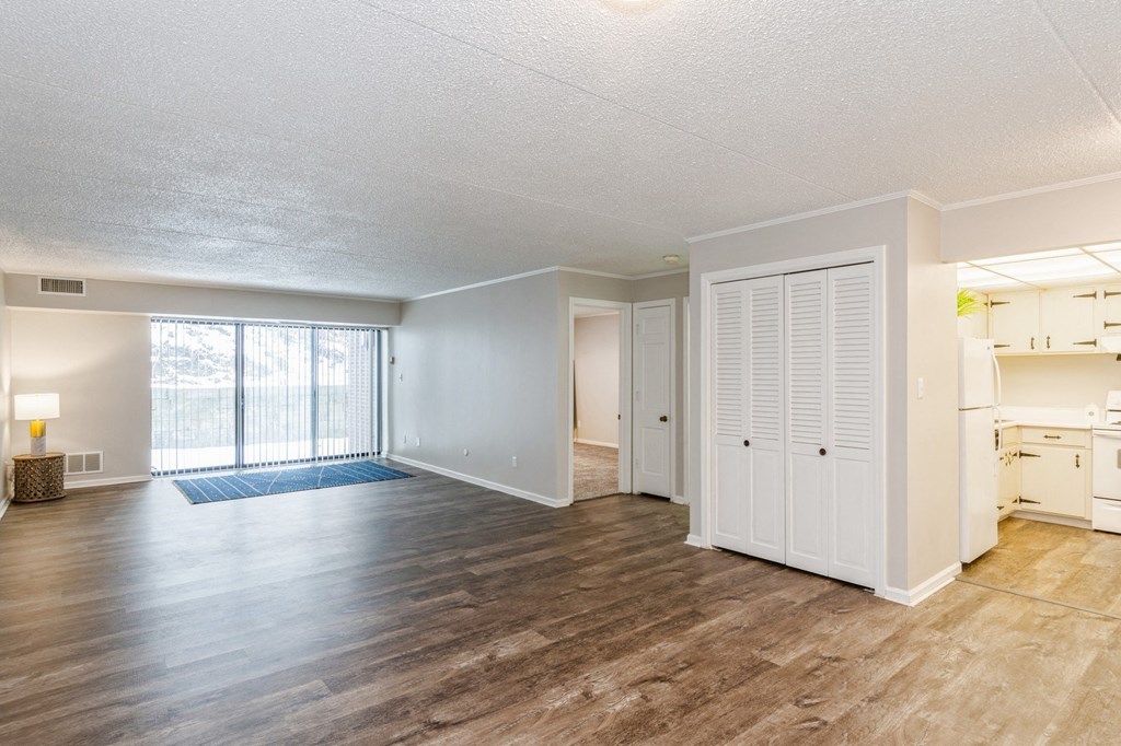 A spacious living room with wooden flooring, a window, and white doors
