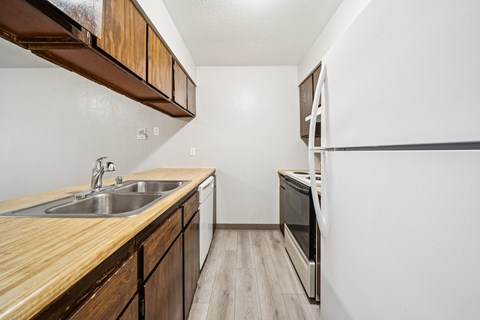 A kitchen with a wooden counter top and stainless steel appliances.