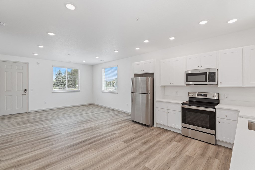 an empty kitchen with white cabinets and stainless steel appliances