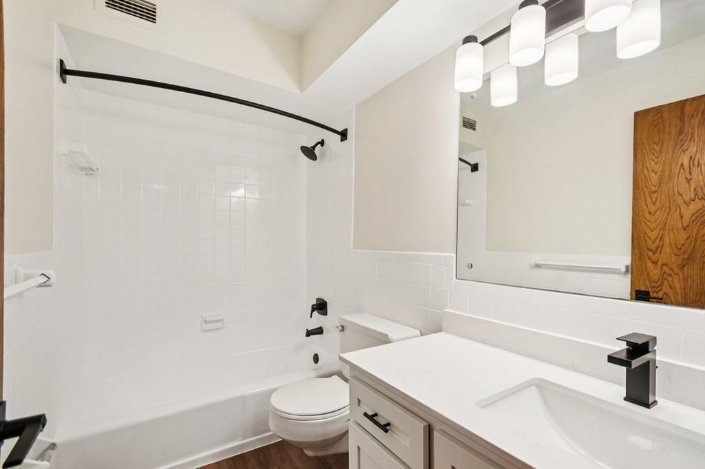 A white bathroom with a toilet, sink, and mirror.