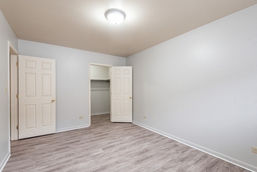 A room with a white ceiling and a wooden floor with two white doors.