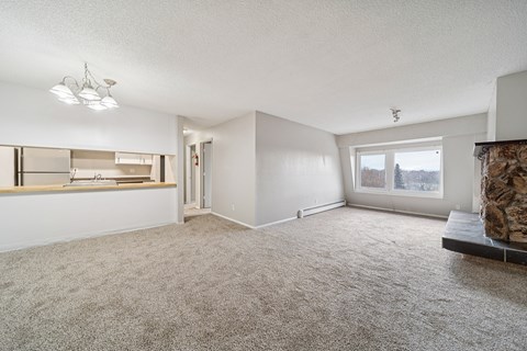 A spacious living room with a fireplace and a large window.