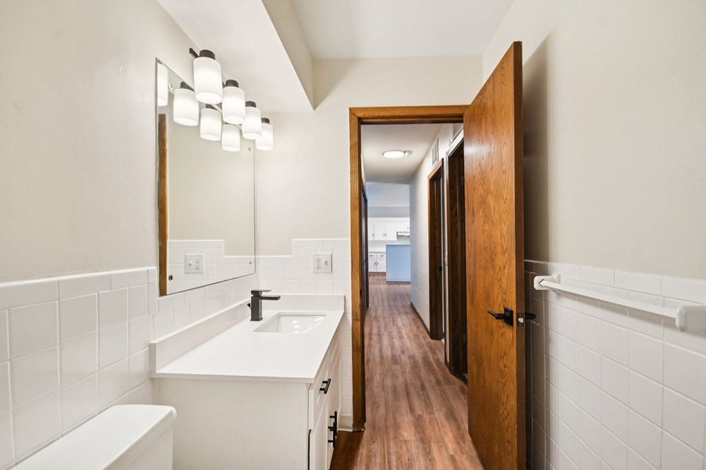 A bathroom with a white counter top and a white sink.