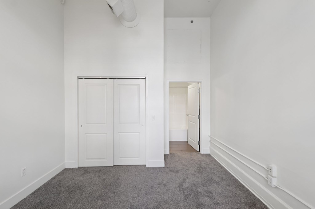 A bedroom with a grey carpet and white walls.