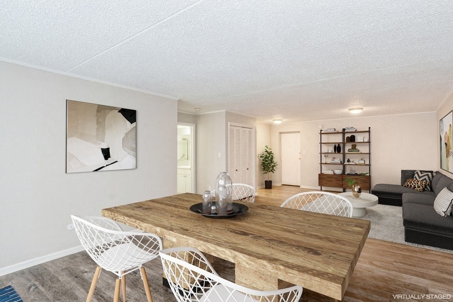 A living and dining room with a sectional sofa, wooden table, and white chairs.