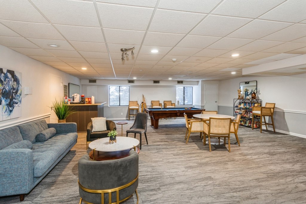 Community room with a grey sofa, a coffee table, and a dining table set up with chairs.