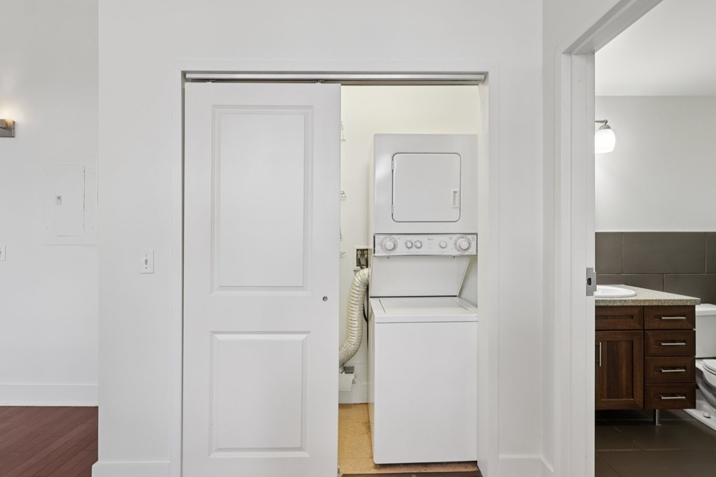 A white door is open to a room with a washer and dryer