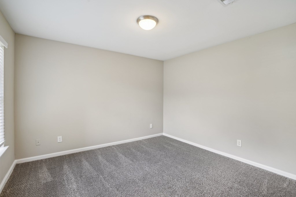A bedroom with a carpeted floor and a ceiling light.