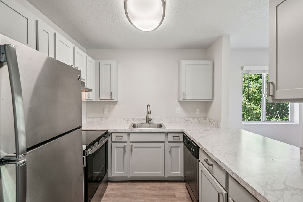 A kitchen with a refrigerator, sink, and cabinets.