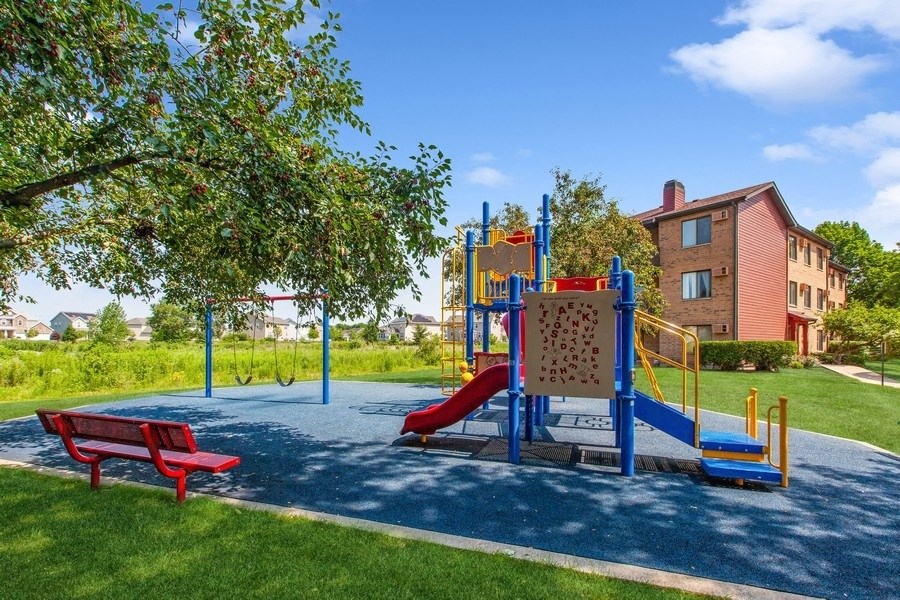 a playground with a red bench and a building in the background