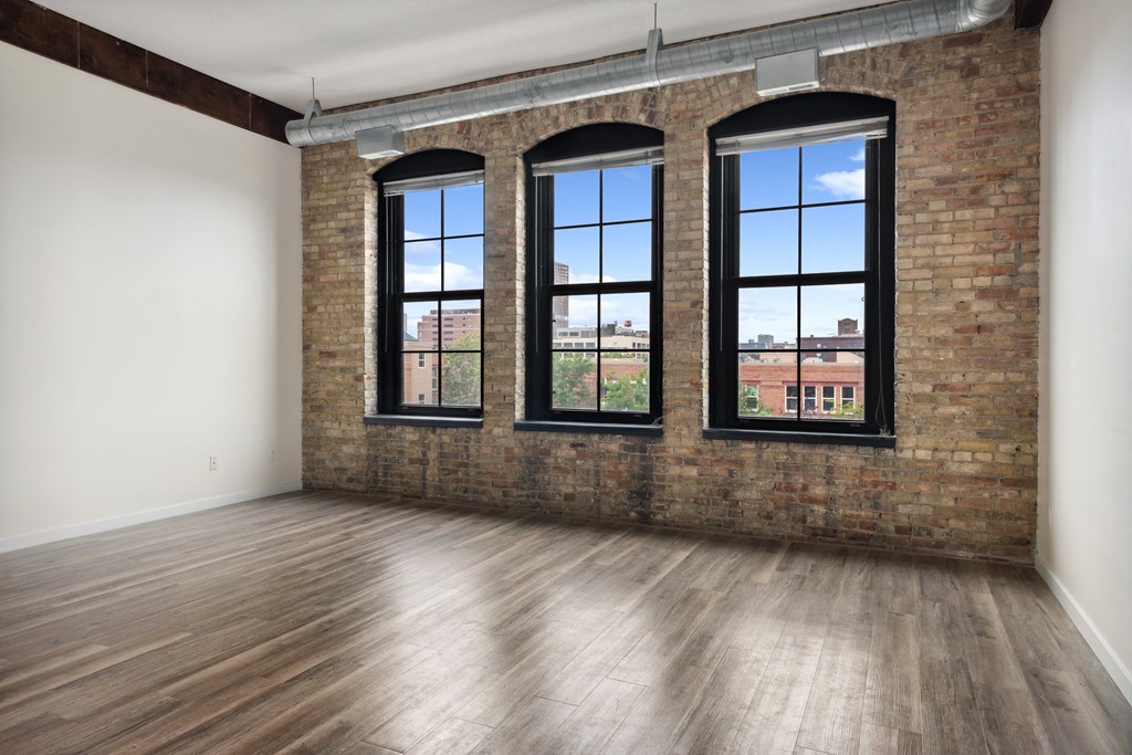 an empty room with a brick wall and three windowsat Gaar Scott Historic Lofts, Minnesota, 55401