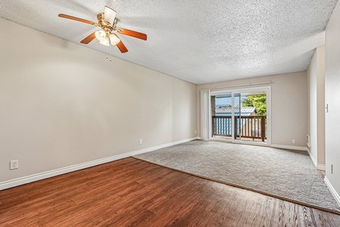 A room with a ceiling fan and wooden flooring.