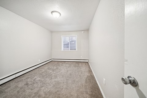 A room with a carpeted floor and a window.