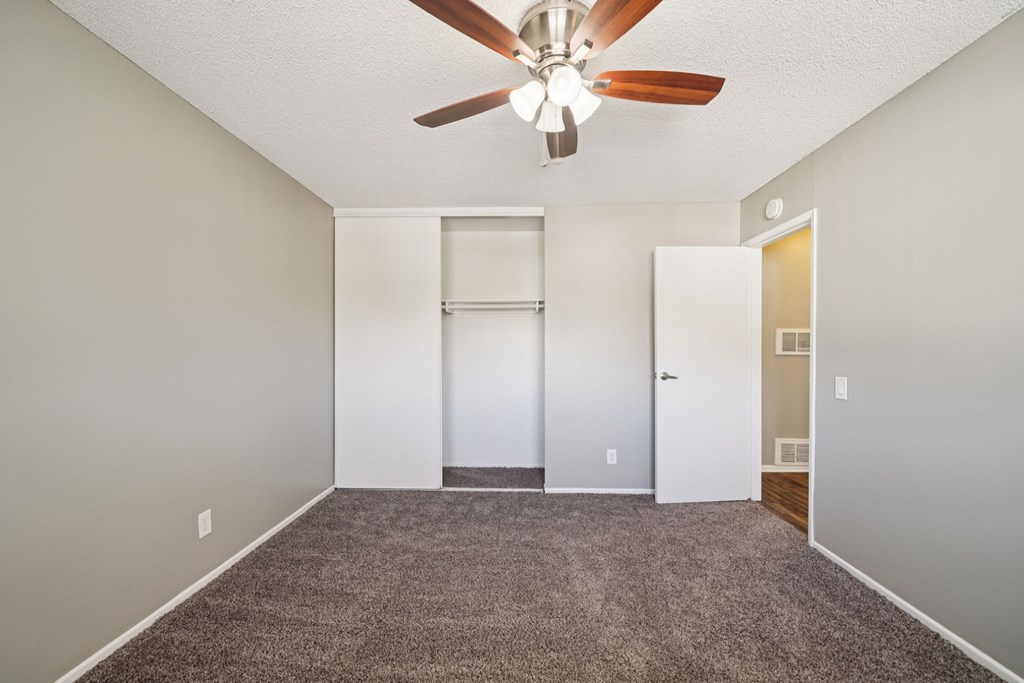 A room with a ceiling fan and carpeted floor.