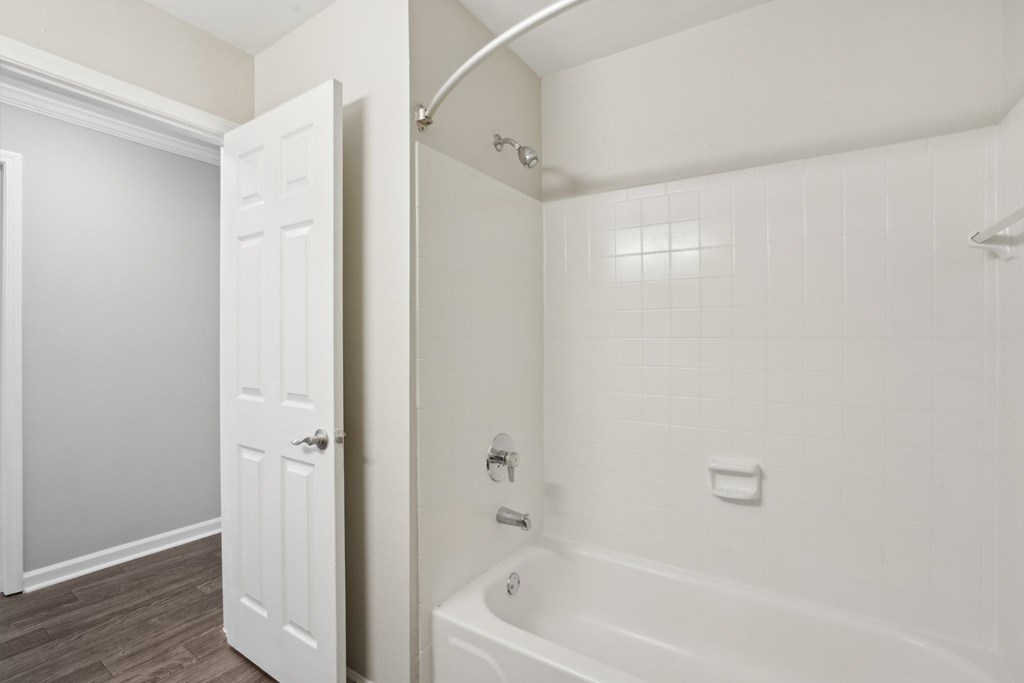 A white bathroom with a tub and a door.