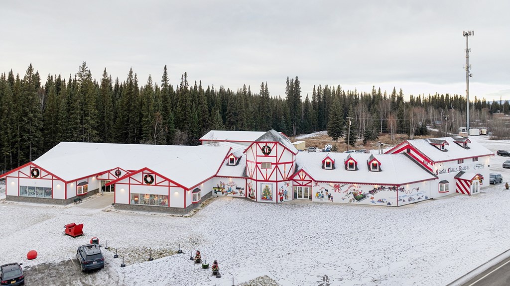A large red and white building with a red roof and white trim is surrounded by snow.