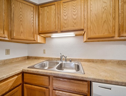 A kitchen with wooden cabinets and a stainless steel sink.
