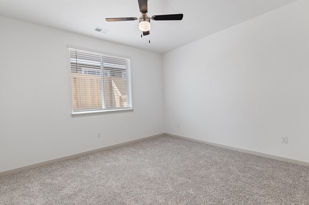 an empty room with a ceiling fan and a window