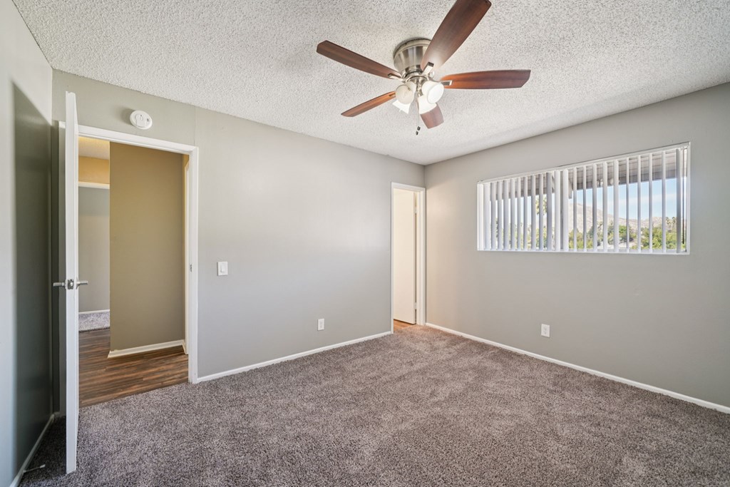 A room with a ceiling fan and a window with blinds.